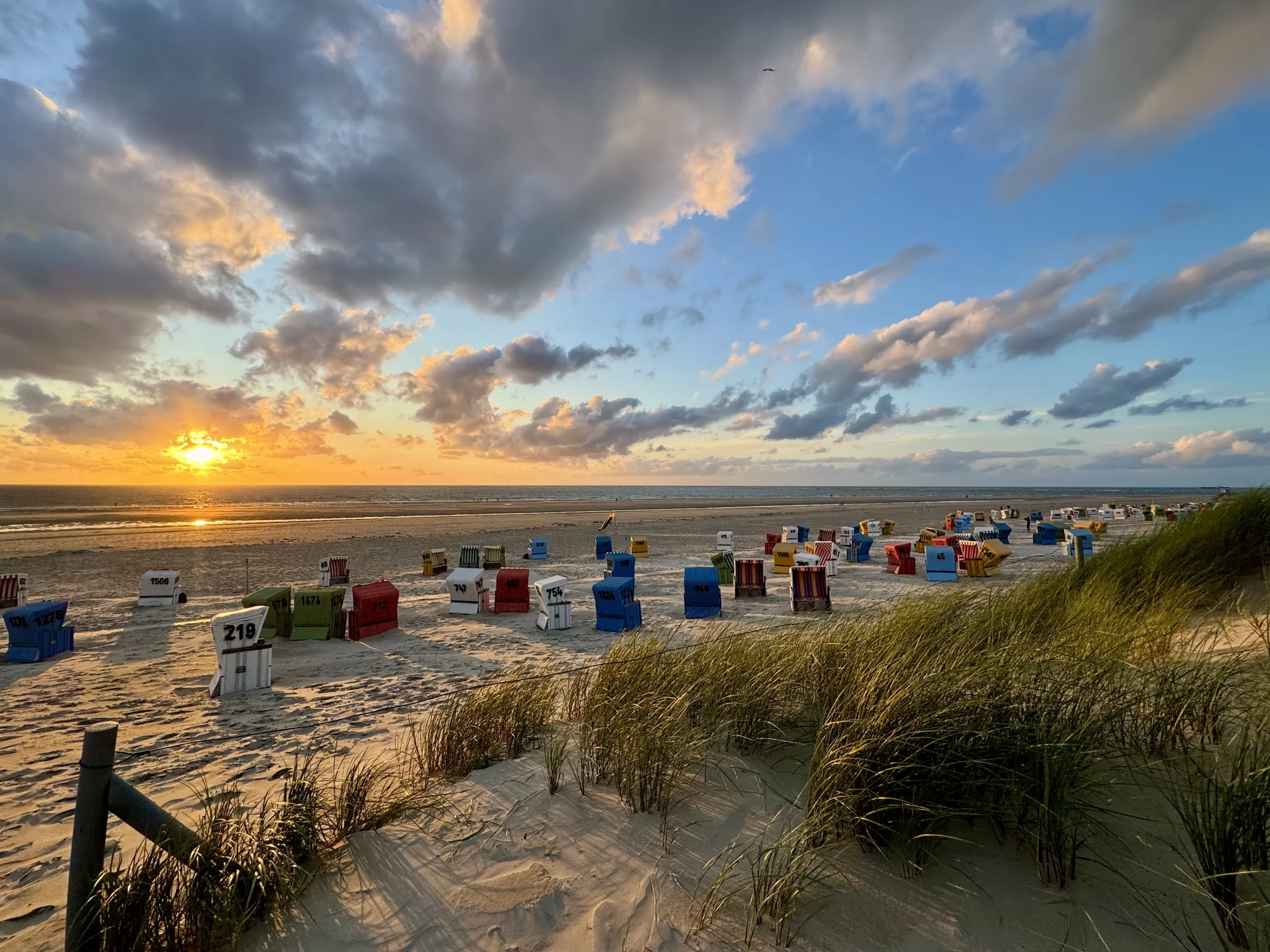 Nordsee Langeoog bei Sonnenuntergang mit Strandkörben und Wolken.