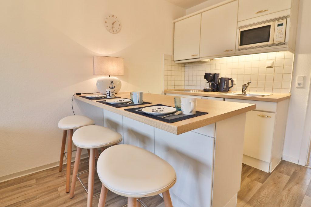 Düne 53 Grad hat eine weiße Küche mit Sitzgelegenheiten (Hockern), großer Lampe und liebevolles Geschirr. Ein Wasserkocher & eine Kaffeemaschine stehen auch zur Verfügung.