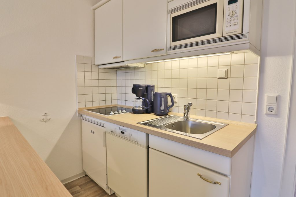 Düne 53 Grad hat eine weiße Küche mit Wasserkocher & Kaffeemaschine & Geschirrspüler.