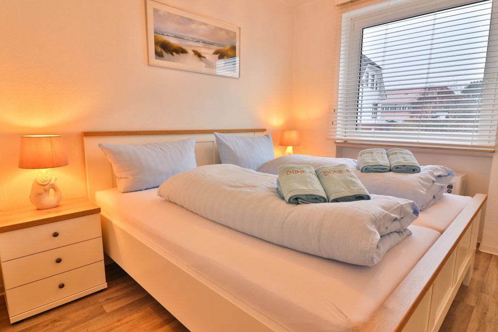 Das große Schlafzimmer der Düne 53 Grad hat ein Doppelbett mit zwei Matratzen, Nachttischlampen und Holzverdunkelungen am Fenster.